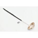 A WHITE METAL LADLE, set with a worn silver coin to the base, fitted with an ebonised handle (
