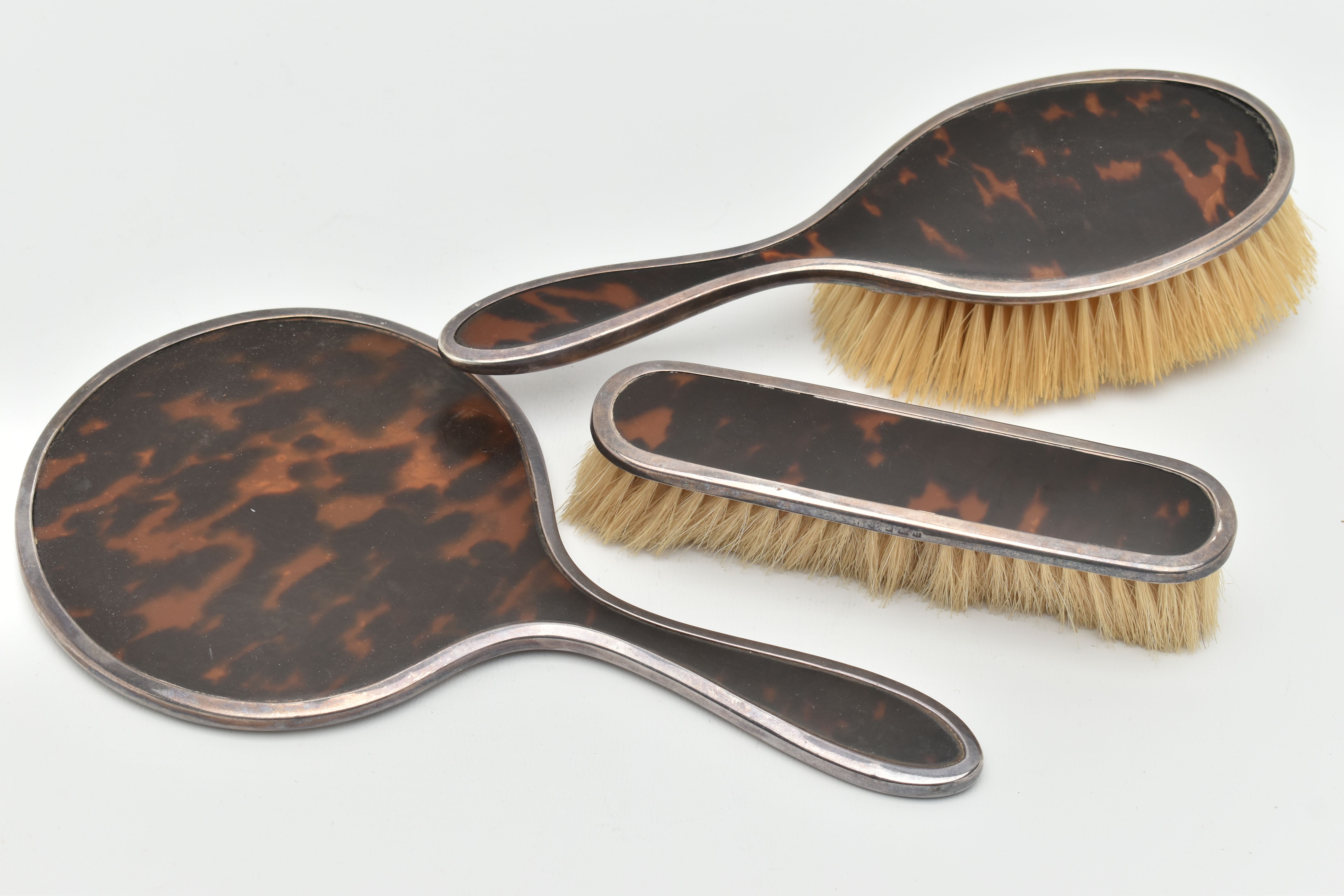 A SILVER AND TORTOISESHELL THREE PIECE VANITY SET, comprising of a hair brush, clothes brush and a