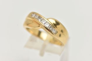 AN 18CT GOLD DIAMOND SET RING, seven princess cut diamonds channel set in yellow gold, cross over