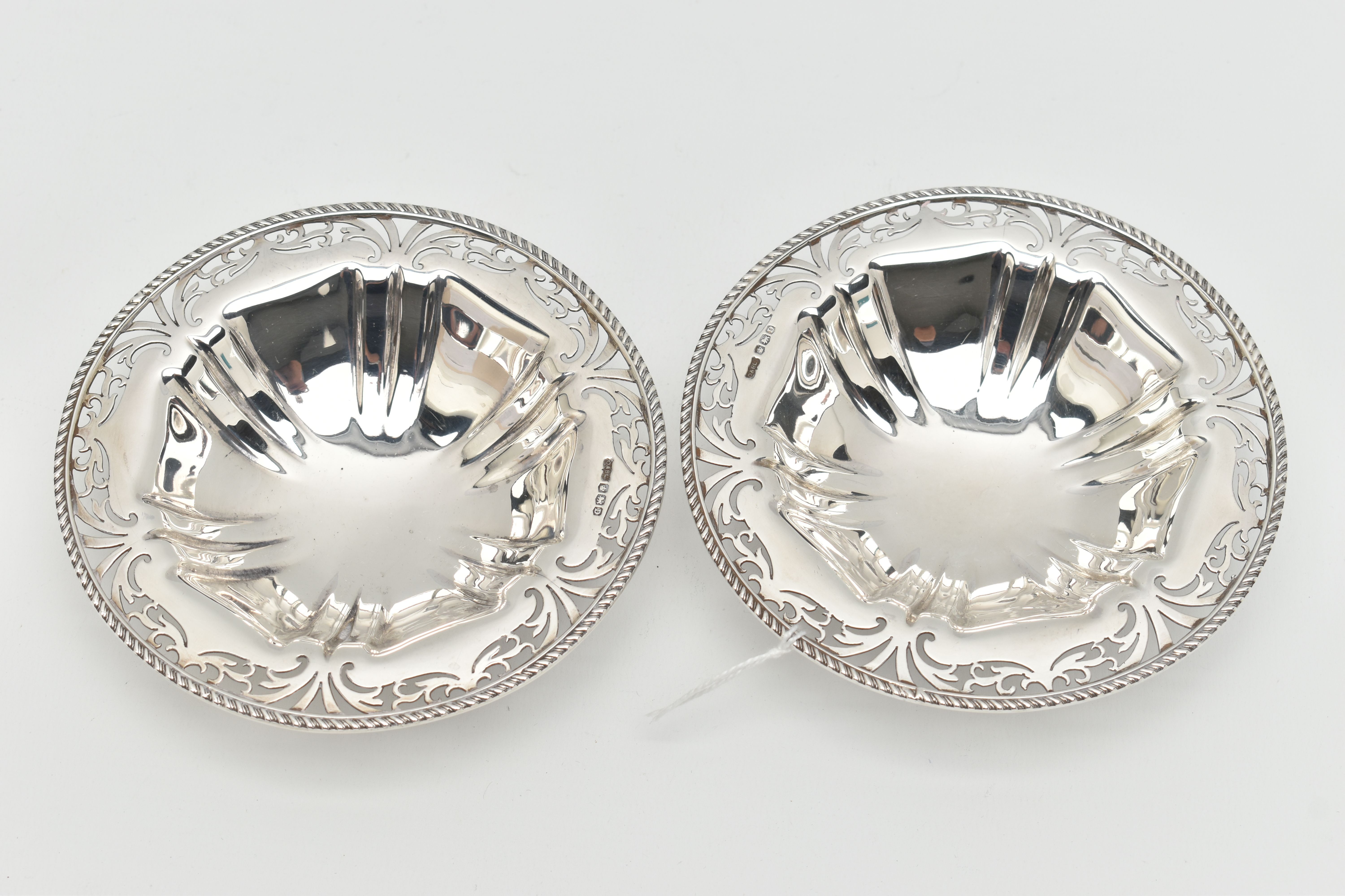 A PAIR OF GEORGE V SILVER CIRCULAR BONBON DISHES, with gadrooned rims and foliate pierced borders,