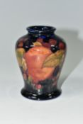 A SMALL MOORCROFT POTTERY 'POMEGRANATE' BALUSTER VASE, with tube lined Pomegranate pattern on a navy