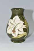 A MOORCROFT POTTERY BALUSTER VASE DECORATED WITH WHITE LILIES ON A GREEN GROUND, impressed marks and