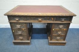 A 20TH CENTURY CARVED OAK TWIN PEDESTAL DESK, with a burgundy leather writing surface, fitted with