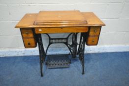 AN OAK CASED SINGER TREADLE SEWING MACHINE, fitted with five drawers and a fold over top, open