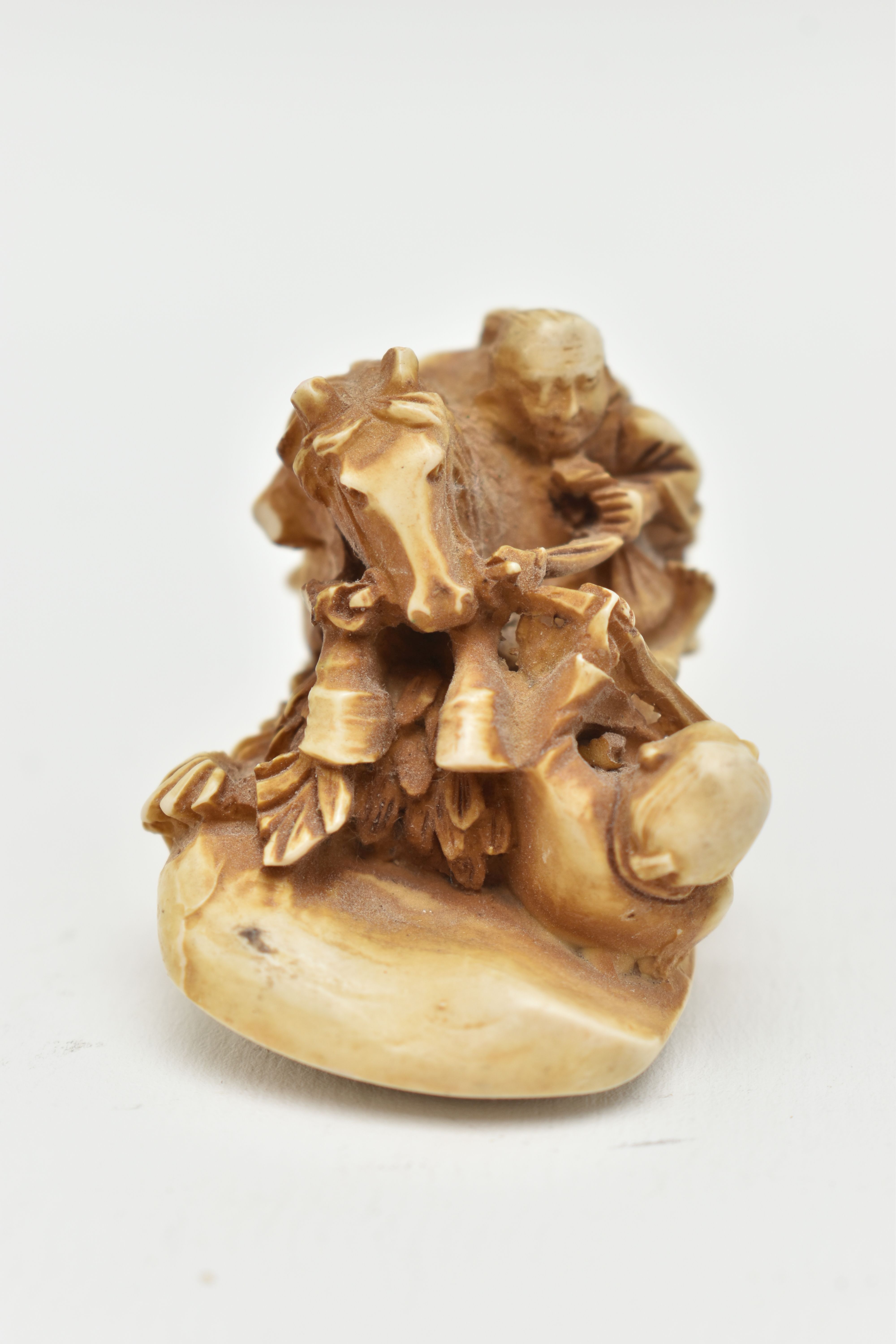 A BONE OKIMONO, a carved ornament depicting a man on a horse over a fallen down man, approximate - Image 2 of 7