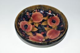 A WILLIAM MOORCROFT SHALLOW FRUIT BOWL DECORATED WITH THE POMEGRANATE PATTERN ON A BLUE / BROWN