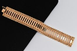 A YELLOW METAL BRACELET, the wide link bracelet with plain polished rectangular links and flower