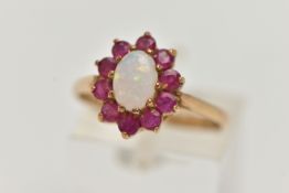 A 9CT GOLD OPAL AND RUBY CLUSTER RING, the central oval opal cabochon within a circular cut ruby