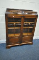 AN EARLY 20TH CENTURY OAK BOOKCASE, with two drawers, above two glazed doors, enclosing three