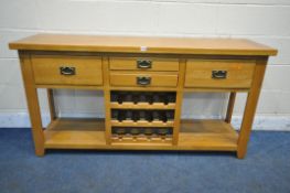A SOLID OAK SIDEBOARD, fitted with an arrangement of four drawers and a central three tier wine
