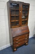 A 20TH CENTURY OAK BUREAU BOOKCASE, the top with double glazed doors, enclosing three adjustable