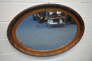A 20TH CENTURY SOLID OAK OVAL WALL MIRROR, with foliate carved and pokerwork frame, width 110cm x