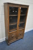 A 20TH CENTURY OAK DOUBLE DOOR BOOKCASE, with two bevelled glass panes above two carved panels,