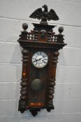 A LATE 19TH CENTURY WALNUT CASED VIENNA WALL CLOCK, with an eagle pediment, above a human mask,