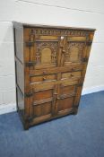 A 20TH CENTURY SOLID OAK CABINET, fitted with two cupboard doors, carved with an archway, a brushing