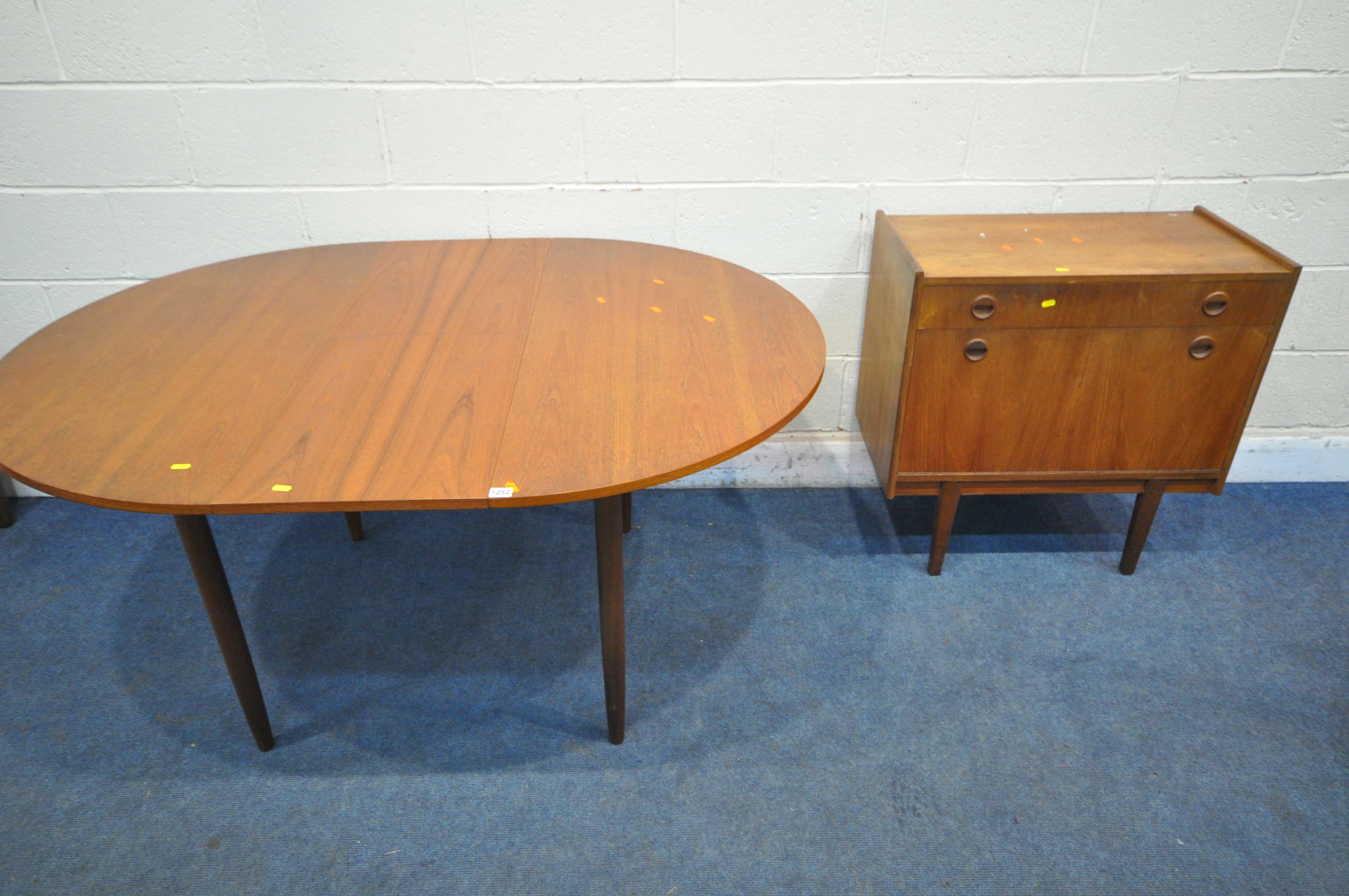 A MID CENTURY TEAK EXTENDING DINING TABLE, with a single fold out leaf, on cylindrical tapered legs,