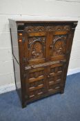 A 20TH CENTURY SOLID OAK DRINKS CABINET, the two double doors , carved with a seated person, an