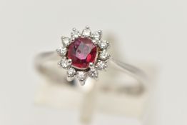 A RUBY AND DIAMOND RING, circular cut ruby prong set in white metal, with a surround of twelve round