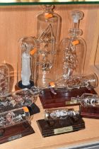 A COLLECTION OF GLASS SHIP IN A BOTTLE ORNAMENTS, comprising eight ships, most with wooden stands,