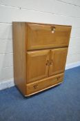 A MID CENTURY ERCOL ELM BUREAU CABINET, the fall front door, enclosing a variety of shelving,