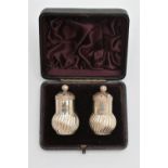 A CASED PAIR OF LATE VICTORIAN SILVER PEPPERETTES, baluster swirl form, pierced covers with ball