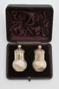 A CASED PAIR OF LATE VICTORIAN SILVER PEPPERETTES, baluster swirl form, pierced covers with ball