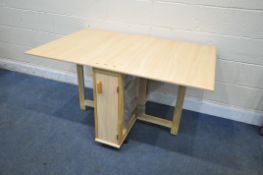 A MODEN BEECH EFFECT DROP LEAF DINING TABLE, with a single door enclosing four bagged fold away