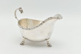 AN ELIZABETH II SILVER SAUCE BOAT, polished design with Celtic pattern to the rim, raised on three