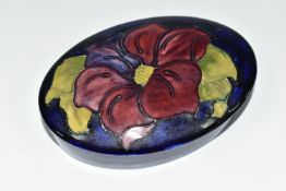 A MOORCROFT POTTERY CLEMATIS TRINKET BOX, the oval box in purple Clematis pattern on a cobalt blue