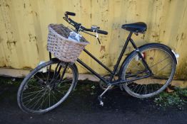 A VINTAGE PHILLIPS BLACK LADIES BICYICLE, with a wicker basket and single gear, along with a hand