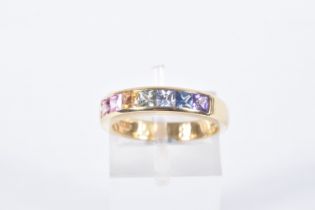 AN 18CT GOLD MULTI GEM RING, set with seven square cut gems in a channel setting, including sapphire