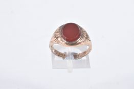 A GENTS SIGNET RING, of an oval form, set with an oval carnelian panel, collet set to the textured