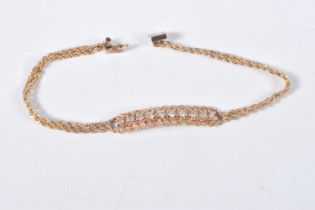 A YELLOW METAL DIAMOND BRACELET, centring on a row of ten round brilliant cut diamonds, estimated