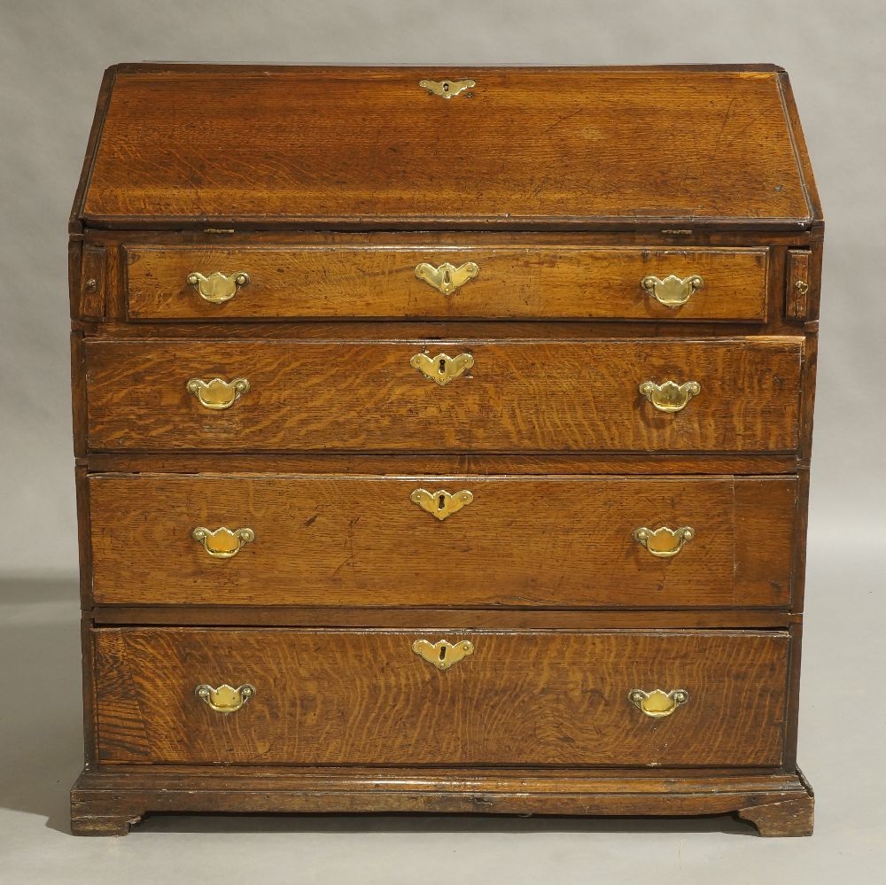 A George III oak bureau, circa 1780, the hinged fall front enclosing fitted interior, above dummy