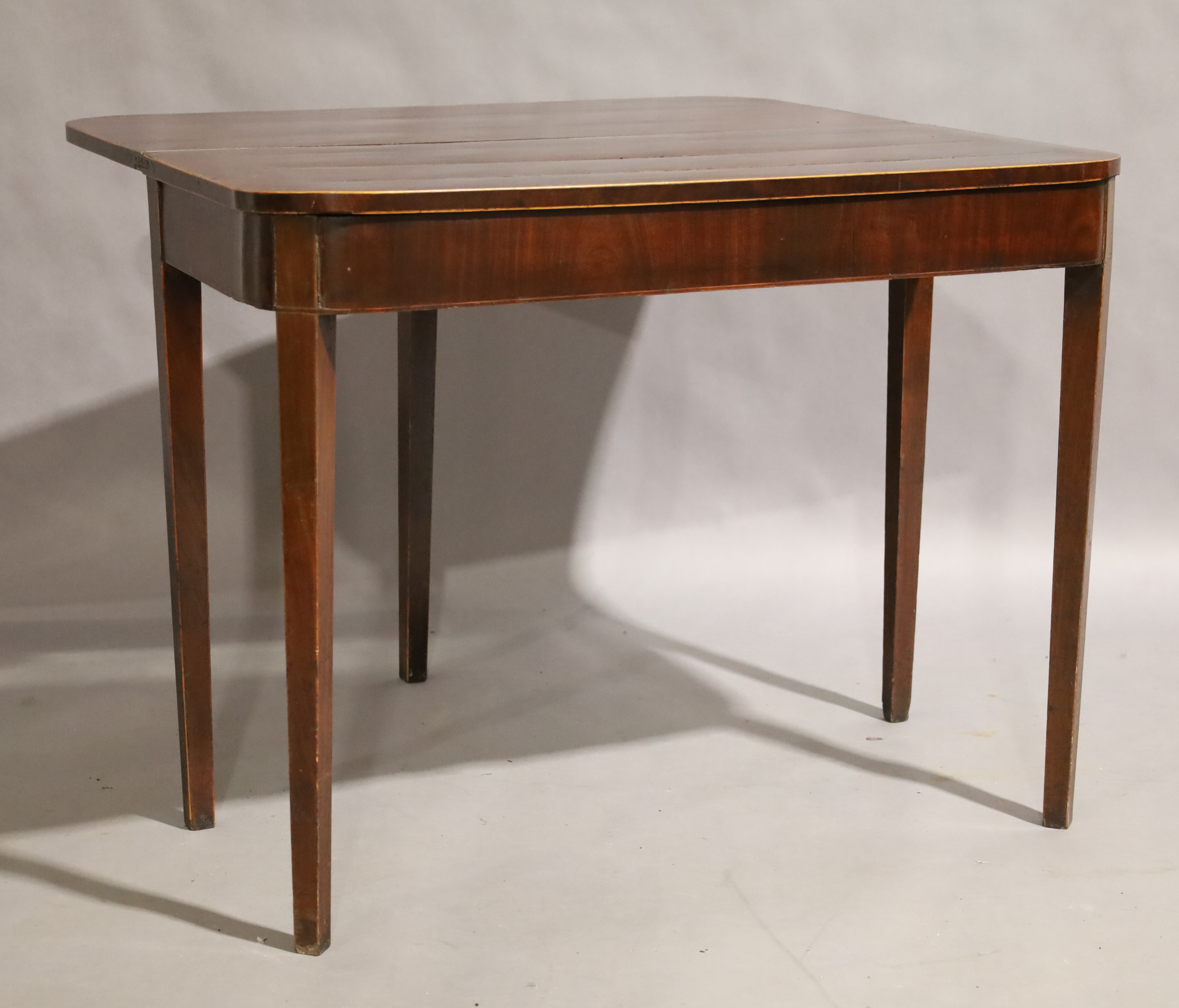 A George III mahogany fold over tea table, circa 1780, boxwood strung, raised on square tapering