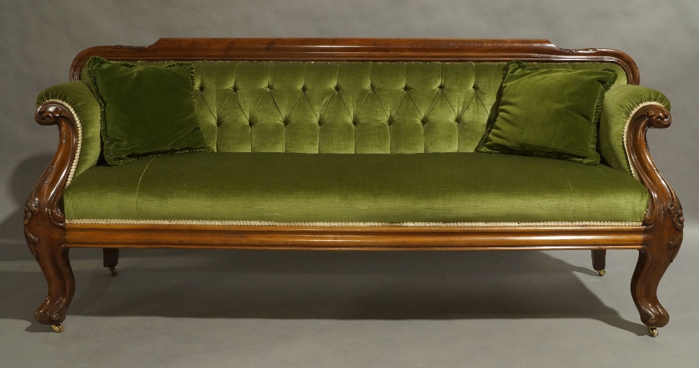 A Victorian mahogany sofa, circa 1860, with green button back velour upholstery, floral carved