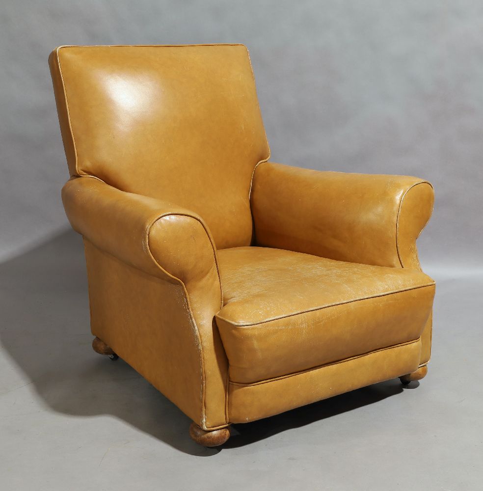 An early 20th century tan leather armchair, circa 1930, raised on bun feet and castorsscratches