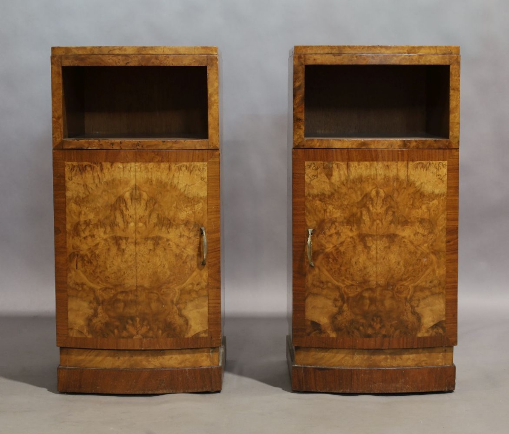 A pair of Art Deco walnut bow fronted bedside cabinets, with open shelf above cupboard door,