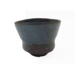 A Japanese shaped blue-green mottle glazed earthenware cup, 20th century, held in a wooden string-