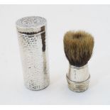 A silver cased travelling shaving brush, London, 1908, of planished cylindrical form with monogram