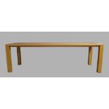 A modern beechwood dining table, rectangular top raised on block square legs, 76cm high, 250cm wide,