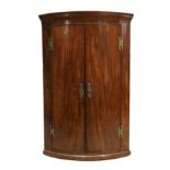 A George III mahogany bowfront hanging corner cupboard