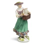 A Meissen porcelain figure of a trinket-seller, c.1745, wearing a green hat, puce bodice, white s...