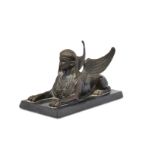 A French bronze model of a recumbent sphinx, 19th century, with decorative breastplate, atop a re...