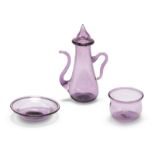 A miniature amethyst glass ewer and a tea bowl and saucer, probably 19th century, the baluster ew...