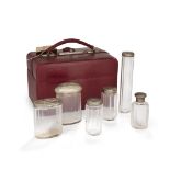 A burgundy leather travelling vanity case fitted with five silver mounted glass bottles, London, ...