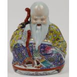 A Chinese porcelain famille rose figure of Shou Lao, 20th century, modelled seated and holding hi...