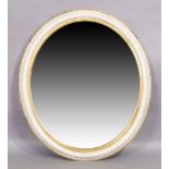 An oval white painted and parcel gilt mirror, early 20th century, the moulded frame set with beve...