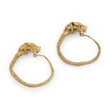 A pair of Hellenistic gold earrings, with bull head terminals, the tapering coiled wire hooking t...
