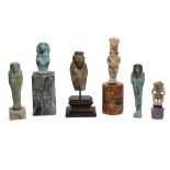 Six Egyptian glazed faience amulets and shabtis, including a large amulet of Bes standing with fe...